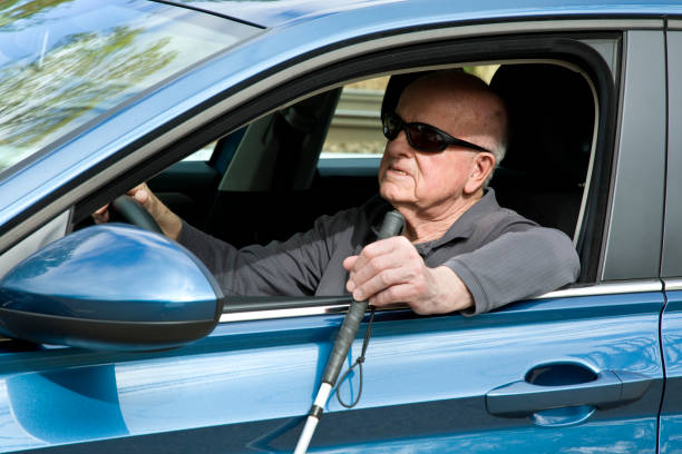 Image of blind person with white cane held outside - driving a car
